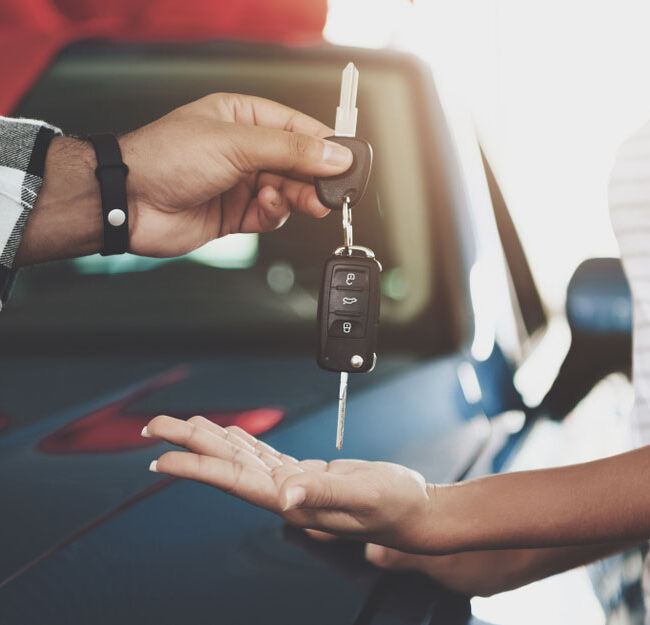 Close up man is giving keys to woman at car dealership