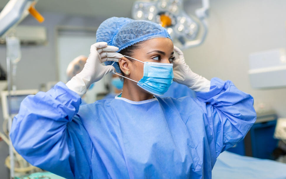 Doctor in operating room wearing scrubs and putting on surgical mask