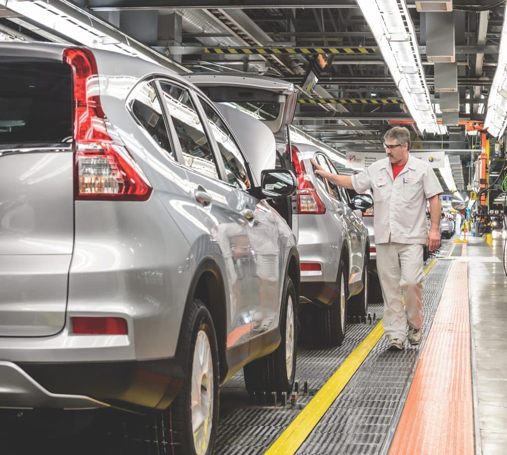Cars coming off the assembly line in a vehicle manufacturing plant and going to quality