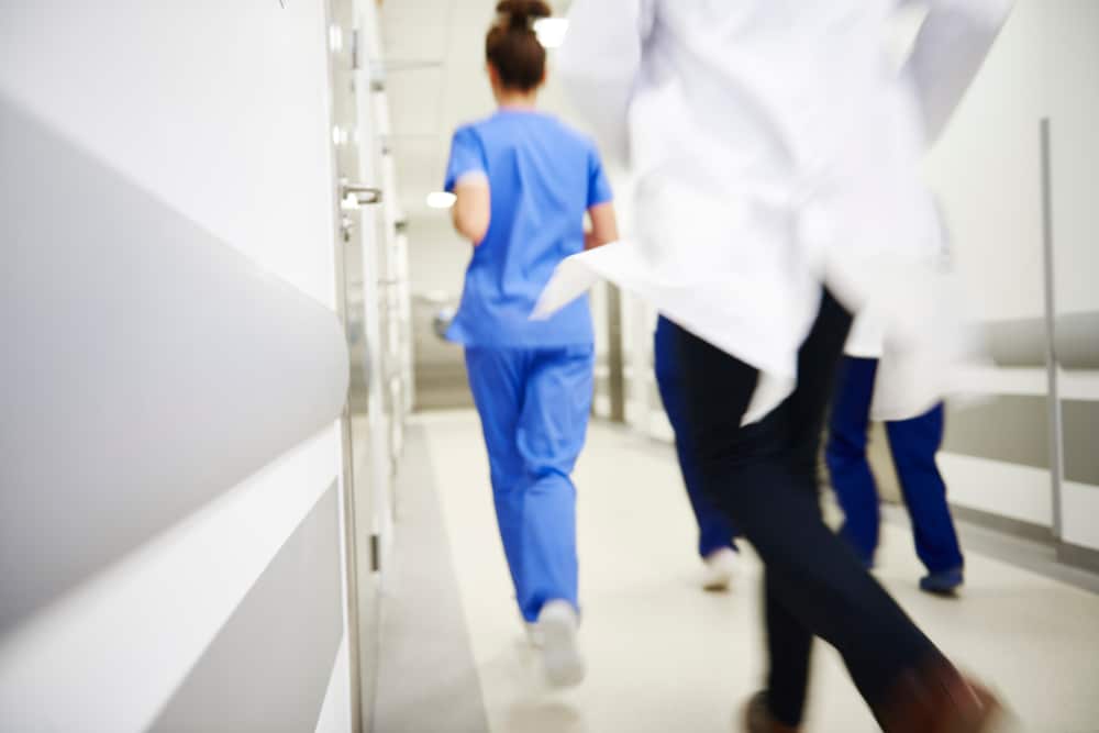 Healthcare staff moving quickly through a hospital hallway during an emergency response.