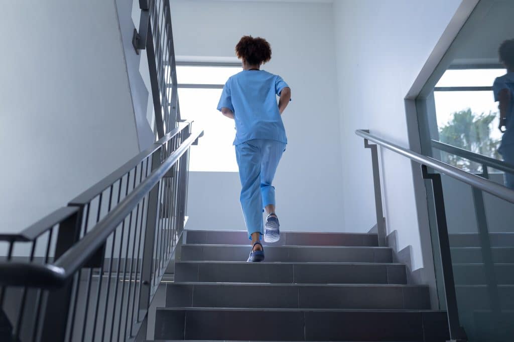 Healthcare worker walking up a hospital stairwell, representing staff safety in healthcare facilities.