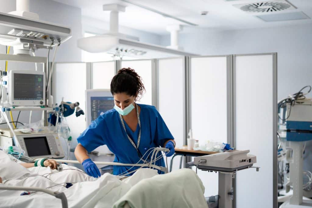 Nurse providing bedside care to a patient in a hospital room.